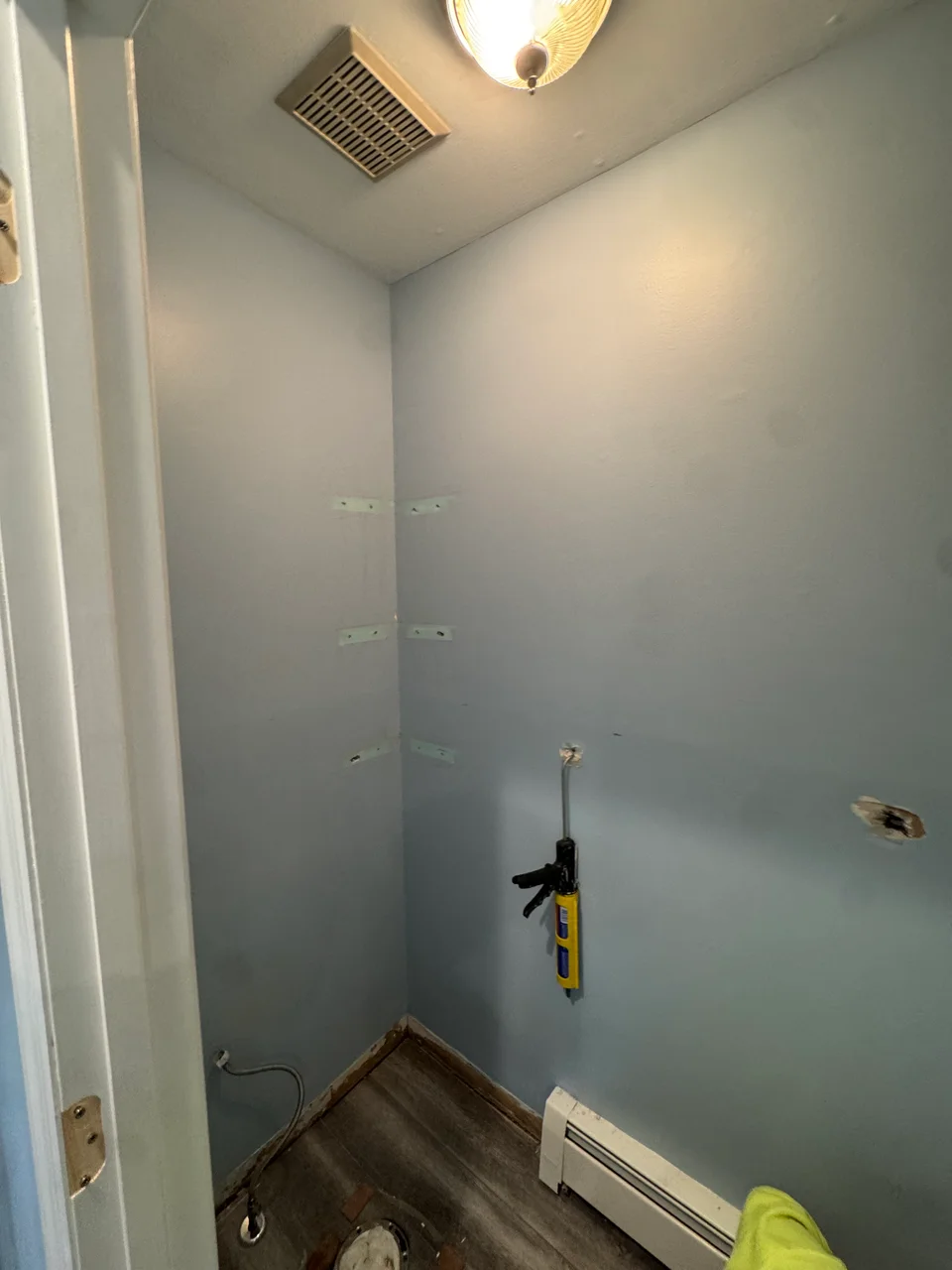 Bathroom before work, with bare walls, removed fixtures and exposed floor