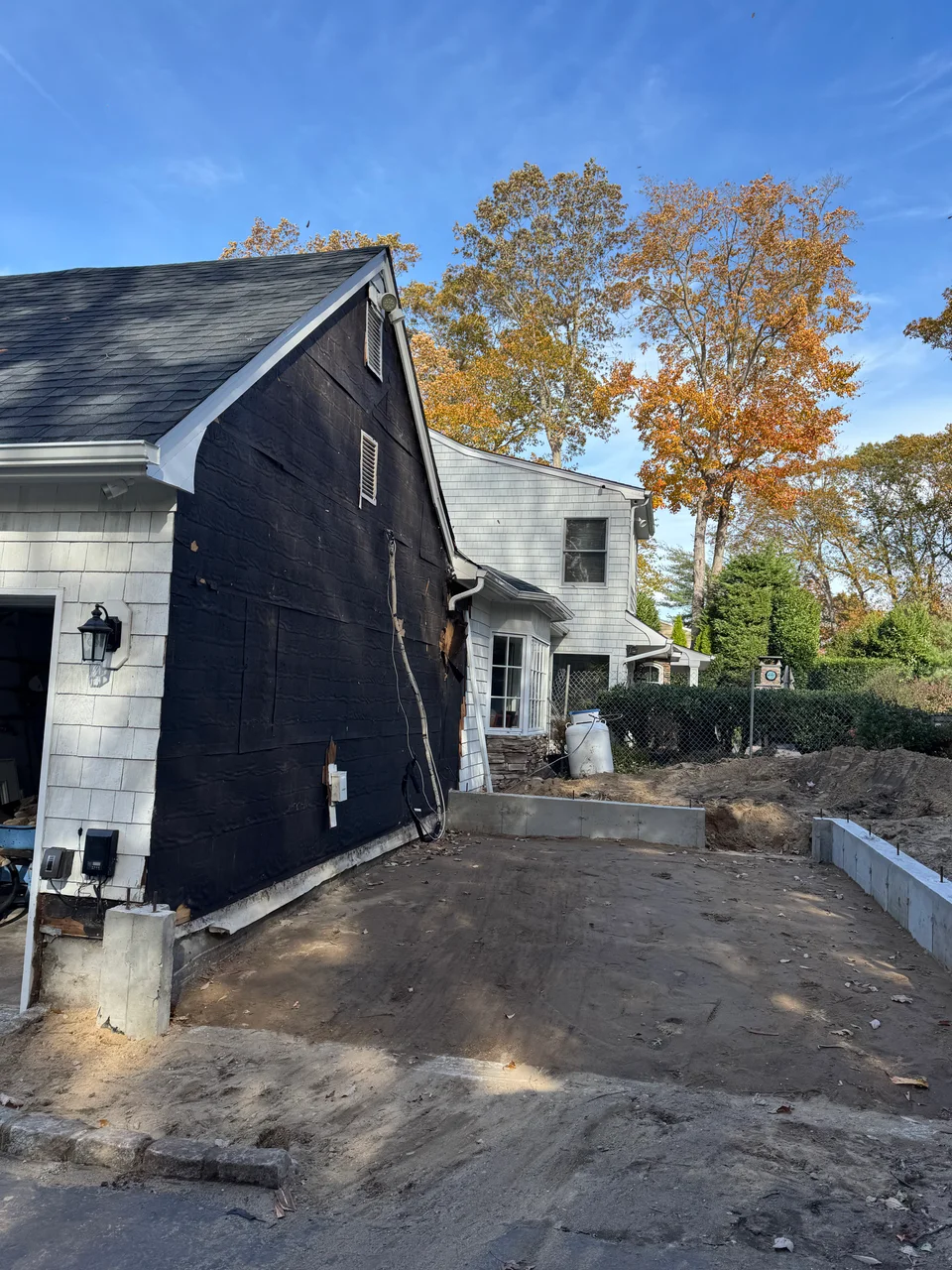 Garage addition site before construction, with the exposed side of the existing garage and foundation work visible